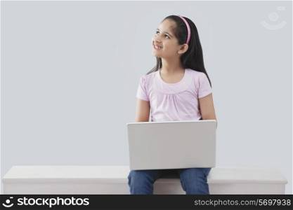 Little girl with a laptop looking up