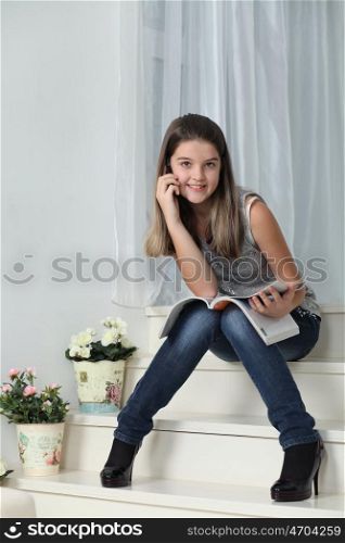 Little girl with a magazine sitting on the stairs