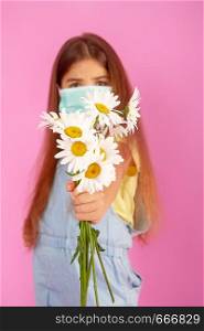 Little girl with allergies to flowers in a medical mask and a bouquet of daisies on a gently pink background. allergy flower mask