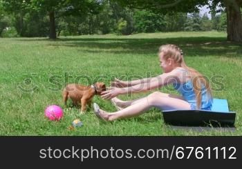 Little girl with american staffordshire terrier puppy dog having fun on grass in summer park