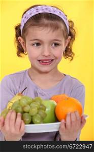 Little girl with an armful of fruit
