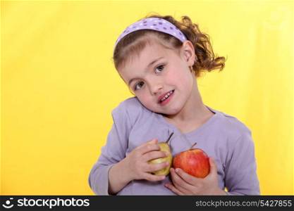 Little girl with apples in hand on yellow background