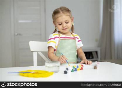 little girl with apron painting