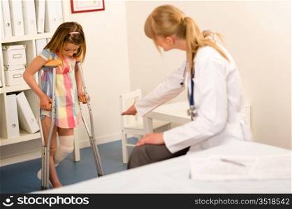 Little girl with bandaged leg walking with crutches surgery office
