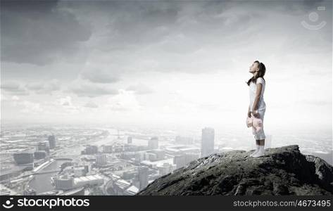 Little girl with bear. Cute girl wearing pajamas with toy bear in hand standing on rock edge