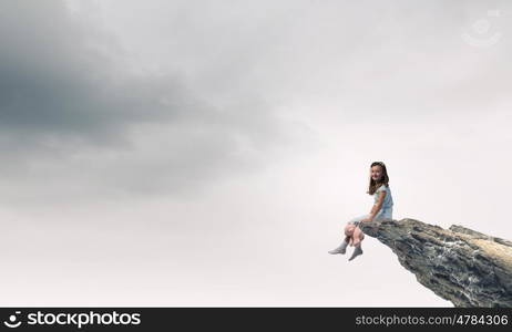 Little girl with bear. Cute girl wearing pajamas with toy bear in hand sitting on rock edge