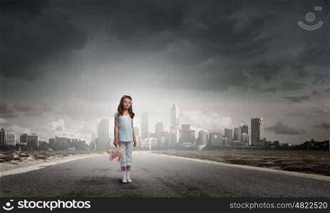 Little girl with bear. Cute girl wearing pajamas with toy bear in hand standing on road