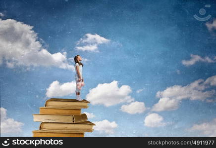 Little girl with bear. Cute girl wearing pajamas with toy bear in hand standing on pile of books