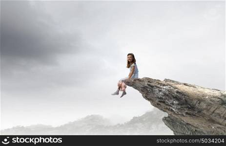 Little girl with bear. Cute girl wearing pajamas with toy bear in hand sitting on rock edge
