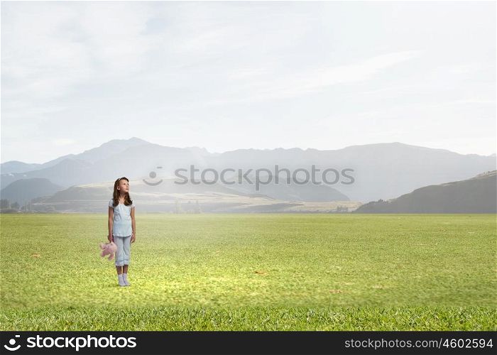 Little girl with bear. Cute girl wearing pajamas with toy bear in hand outdoors