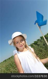 Little girl with blue wind wheel in countryside