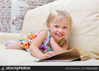 Little girl with book on sofa