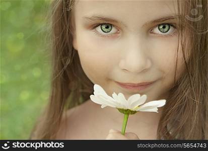 Little Girl With Camomile Looking At The Camera. Close-Up.