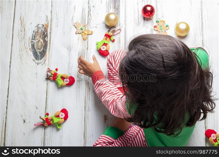 Little girl with Christmas pajamas playing with Christmas decorations