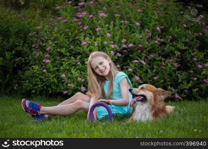 little girl with corgi fluffy on the lawn. Dog outdoors