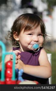 Little girl with dummy at at the playground