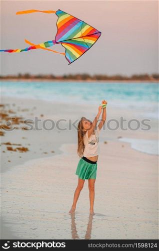 Little girl with flying kite on tropical beach. Kid play on ocean shore. Child with beach toys.. Little running girl with flying kite on tropical beach. Kid play on ocean shore.