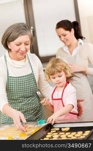 Little girl with grandmother baking cookies put on tray