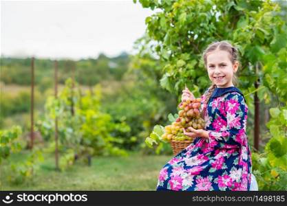Little girl with grapes in the garden. Happy cute baby eating grapes.. Little girl with grapes in the garden.