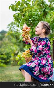 Little girl with grapes in the garden, Happy cute baby eating grapes. Little girl with grapes in the garden.