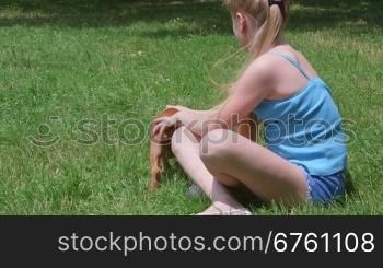 Little girl with her american staffordshire terrier puppy dog on a grass