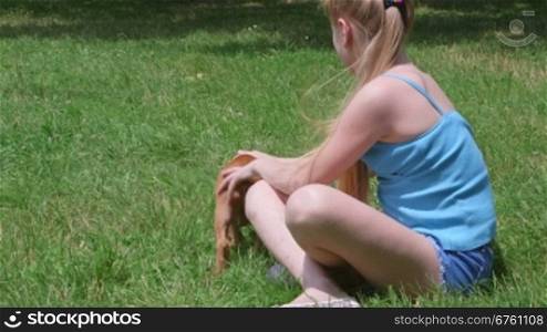 Little girl with her american staffordshire terrier puppy dog on a grass