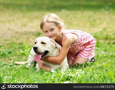 little girl with her dog. A little blond girl with her pet dog outdooors in park
