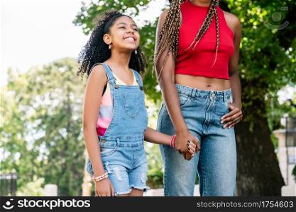Little girl with her mother having good time together on a walk outdoors on the street.