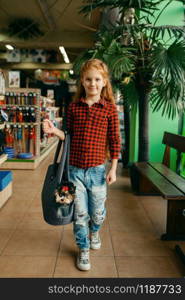 Little girl with her puppy in bag, pet store. Child buying equipment in petshop, accessories for domestic animals. Little girl with her puppy in bag, pet store