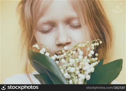 little girl with lilies of the valley in hands