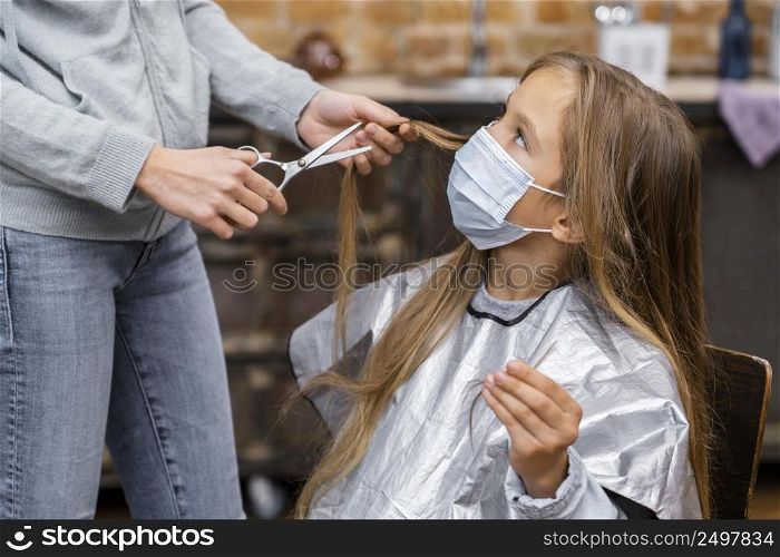 little girl with medical mask getting haircut