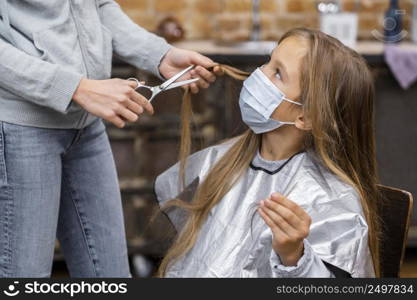 little girl with medical mask getting haircut