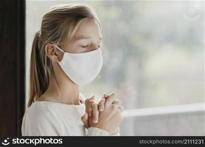 little girl with medical mask praying