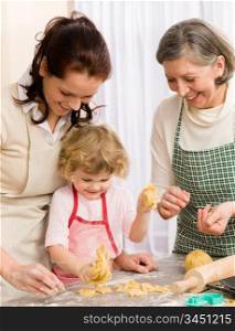 Little girl with mother cutting out cookies in kitchen