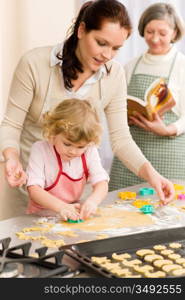 Little girl with mother cutting out cookies in kitchen