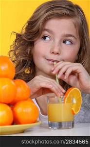 Little girl with oranges and a glass of juice