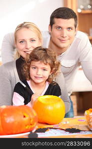 Little girl with parents preparing pumpkin for Halloween