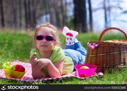 Little girl with picnic basket and grape at forest