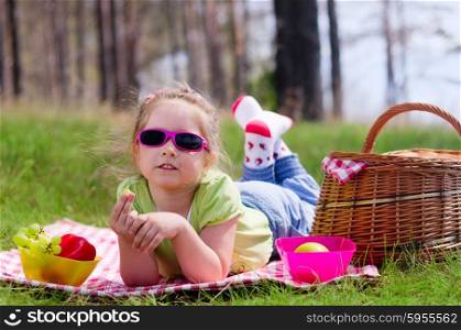 Little girl with picnic basket and grape at lawn