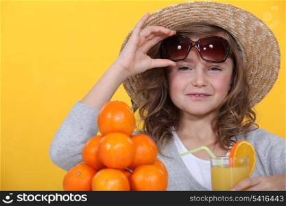 Little girl with pile of oranges wearing straw hat