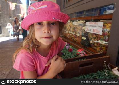 Little girl with pink hat in front of a grocery store, San Marino