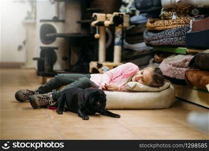 Little girl with puppy are sleep in pet shop. Kid with dog in petshop, goods for domestic animals. Little girl with puppy are sleep in pet shop