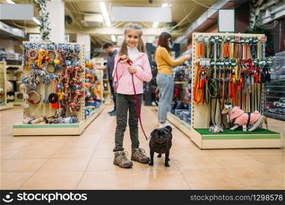 Little girl with puppy in pet shop, friendship. Kid with dog chooses accessories in petshop, caring for domestic animals. Little girl with puppy in pet shop, friendship
