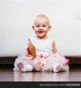 Little girl with red shoes. Lesson of walking. Sweet adorable baby girl thinking about make step. Little child toddler wearing princess dress with red small shoes.
