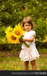Little girl with sunflowers in the garden