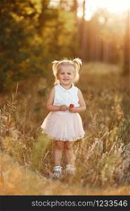 little girl with two tails. The girl walks in the park at sunset. nice little baby in a pink skirt. little girl with two tails. nice little baby in a pink skirt. The girl walks in the park at sunset