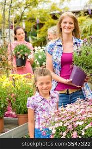 Little girl with young woman buying potted flower at market