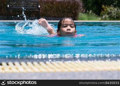 Little girls enjoy swimming in the pool. Cute Asian girl wearing a life jacket is having fun playing in the outdoor pool. Healthy Summer Activities for Kids.
