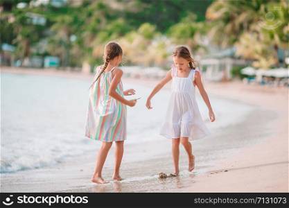 Little girls fooling around on the beach on summer vacation. Little girls having fun enjoying vacation on tropical beach