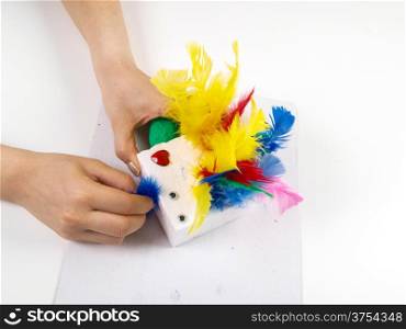 Little girls hands playing with colorful feathers, creating Easter decoration